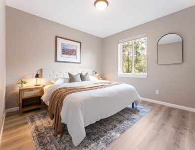 Bright guest bedroom with king bed, forest views, and warm wood furnishings at Trail House golf rental