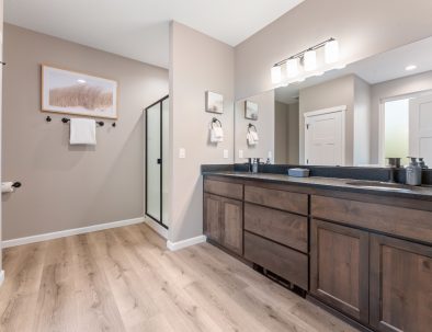 Spa-like master bathroom with double vanity, walk-in shower, and skylight at Trail House golf rental