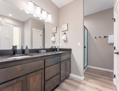 Master bathroom with double vanity, walk-in shower, and wood cabinetry at Bandon's Trail House