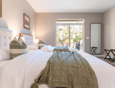 Luxurious master bedroom with two queen beds, patio access, and forest views at Trail House