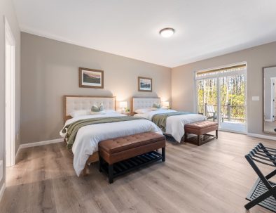Spacious guest bedroom with two queen beds, patio access, and forest views at Bandon's Trail House