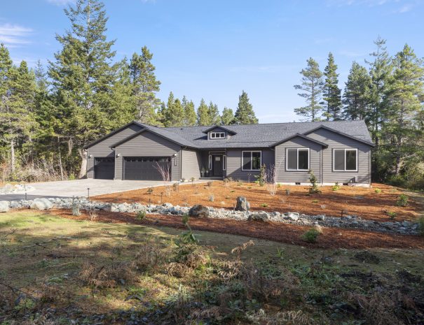 Front view of Trail House 5-bedroom rental with garage and natural Oregon landscaping