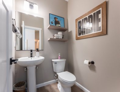 Half bath with pedestal sink, toilet, and golf-themed décor at Bandon Dunes vacation rental