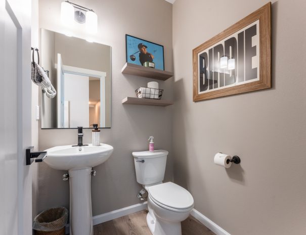 Half bath with pedestal sink, toilet, and golf-themed décor at Bandon Dunes vacation rental