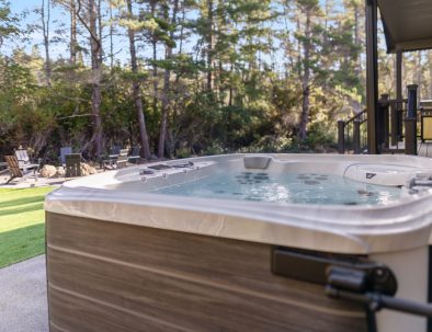Hot tub on backyard patio with forest views and fire pit seating at Trail House golf rental