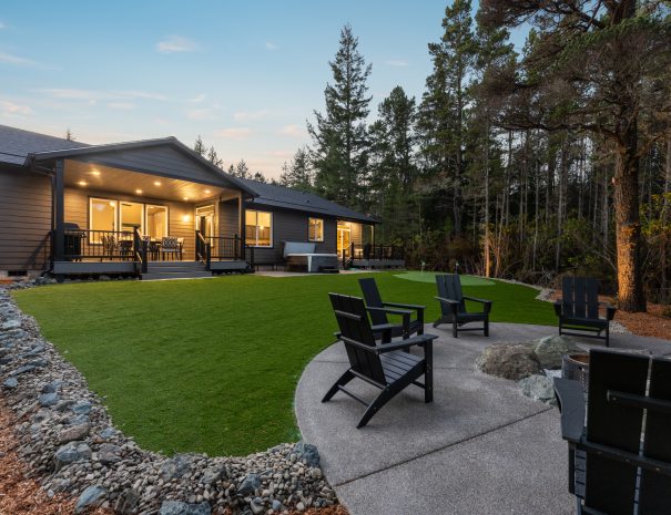 Backyard with Adirondack chairs, putting green, and fire pit at Trail House near Bandon Dunes